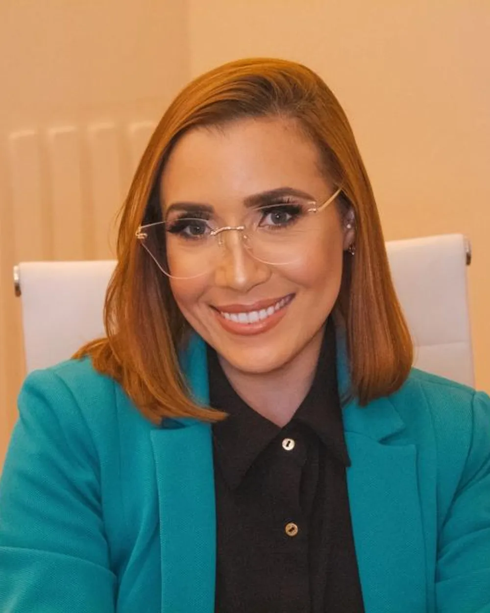 Dra. Kamila Flor sorrindo, sentada na sala de atendimento